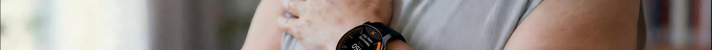 An older man holds his wrist up at chest height while his watch takes a blood pressure reading